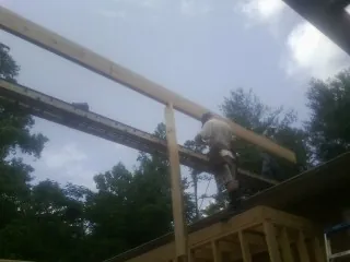 Carpenter setting a ridge beam over a new addition frame — Ice Dam Removal by Roofing Brothers in Wyandanch