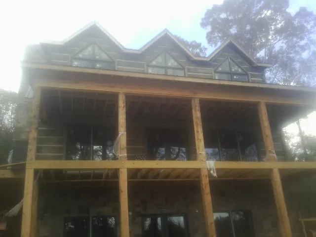 Dormers and porch framing on a large log home under construction — Roof Coating work by our crew in Wyandanch