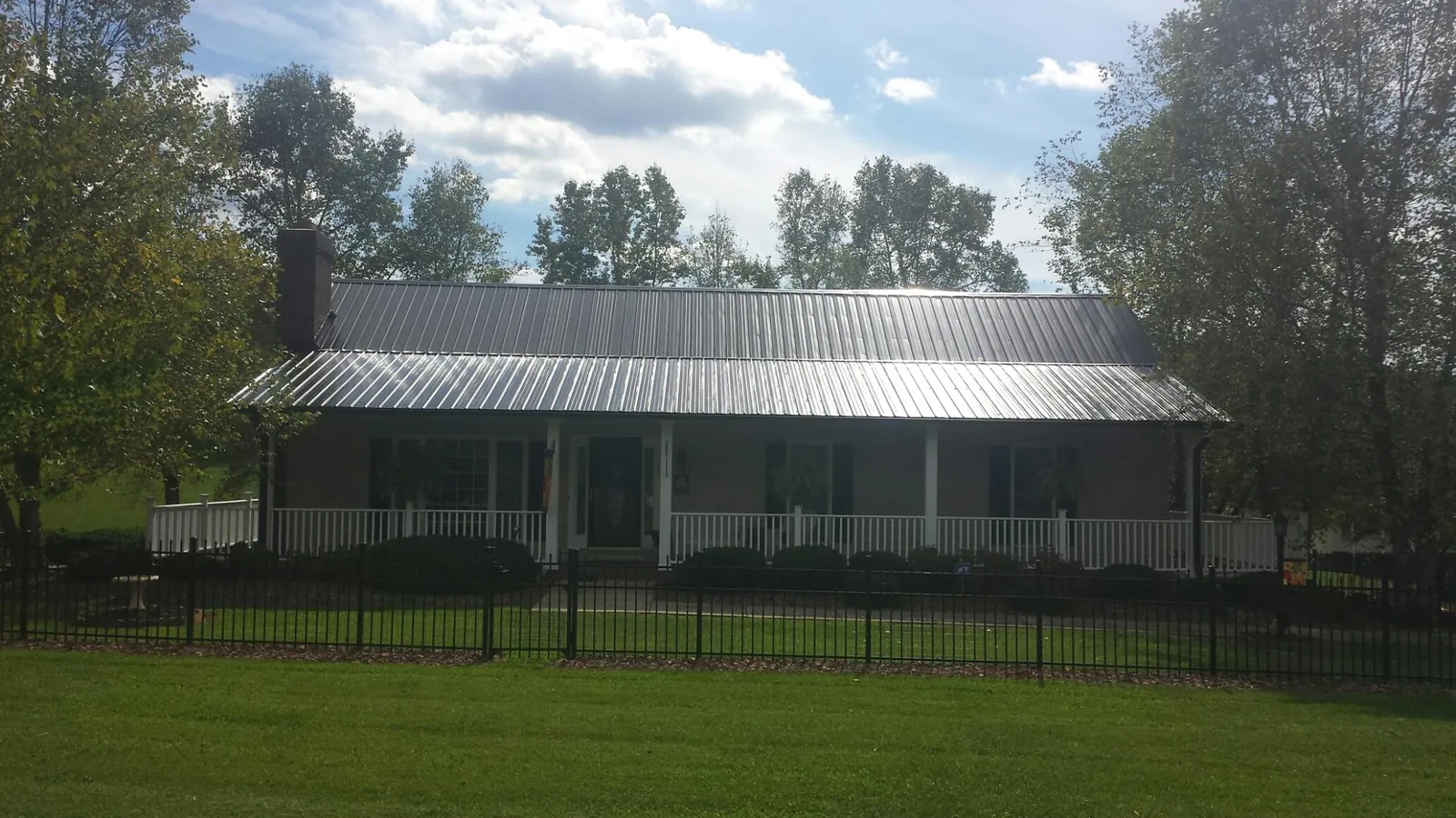 Gray metal roof on a brick ranch with a full width front porch — Gutter Guard Installation work by our crew in Wyandanch