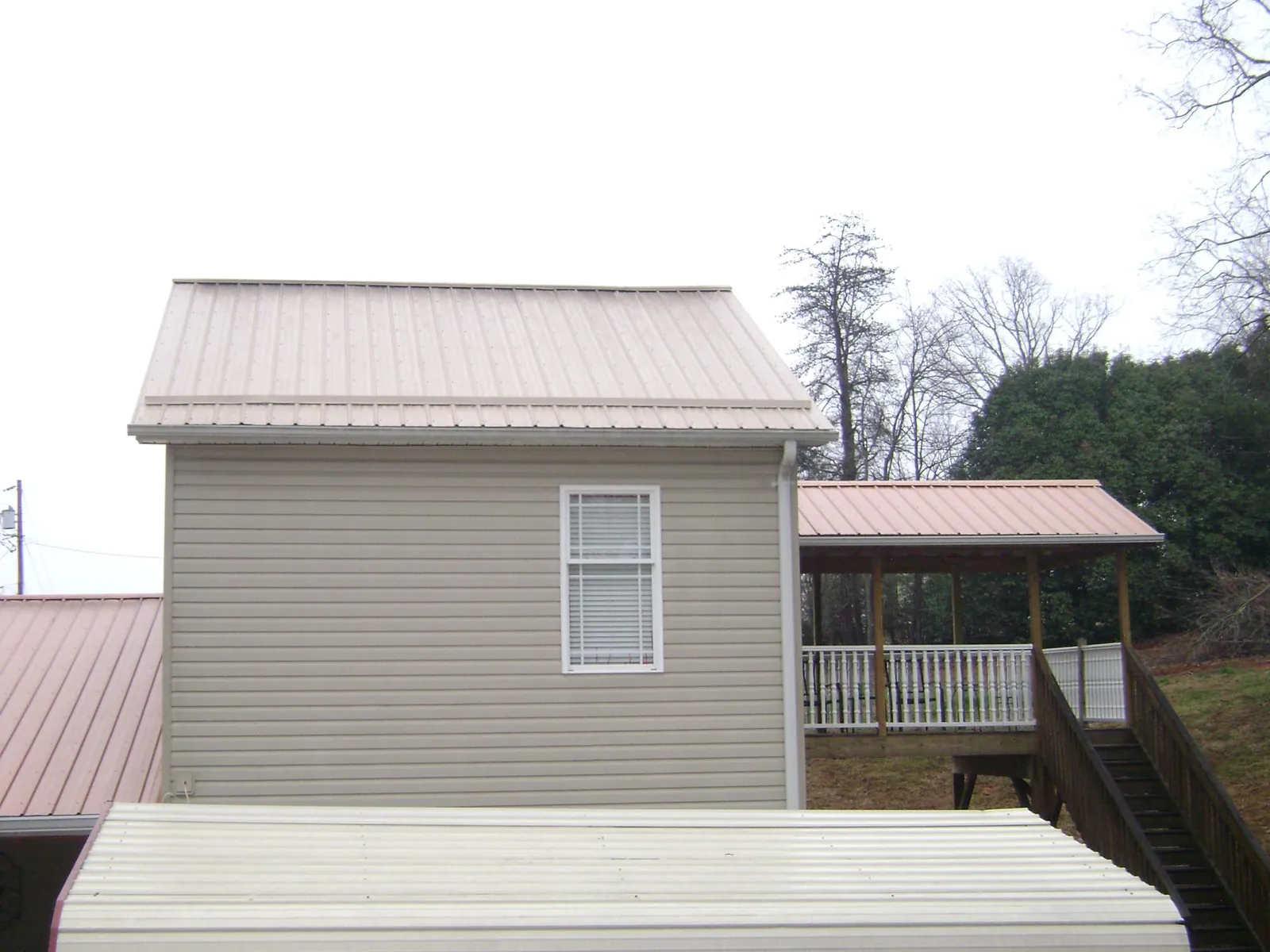 Tan metal roofs on a two story addition and attached porch, from a Roof Replacement job in Wyandanch