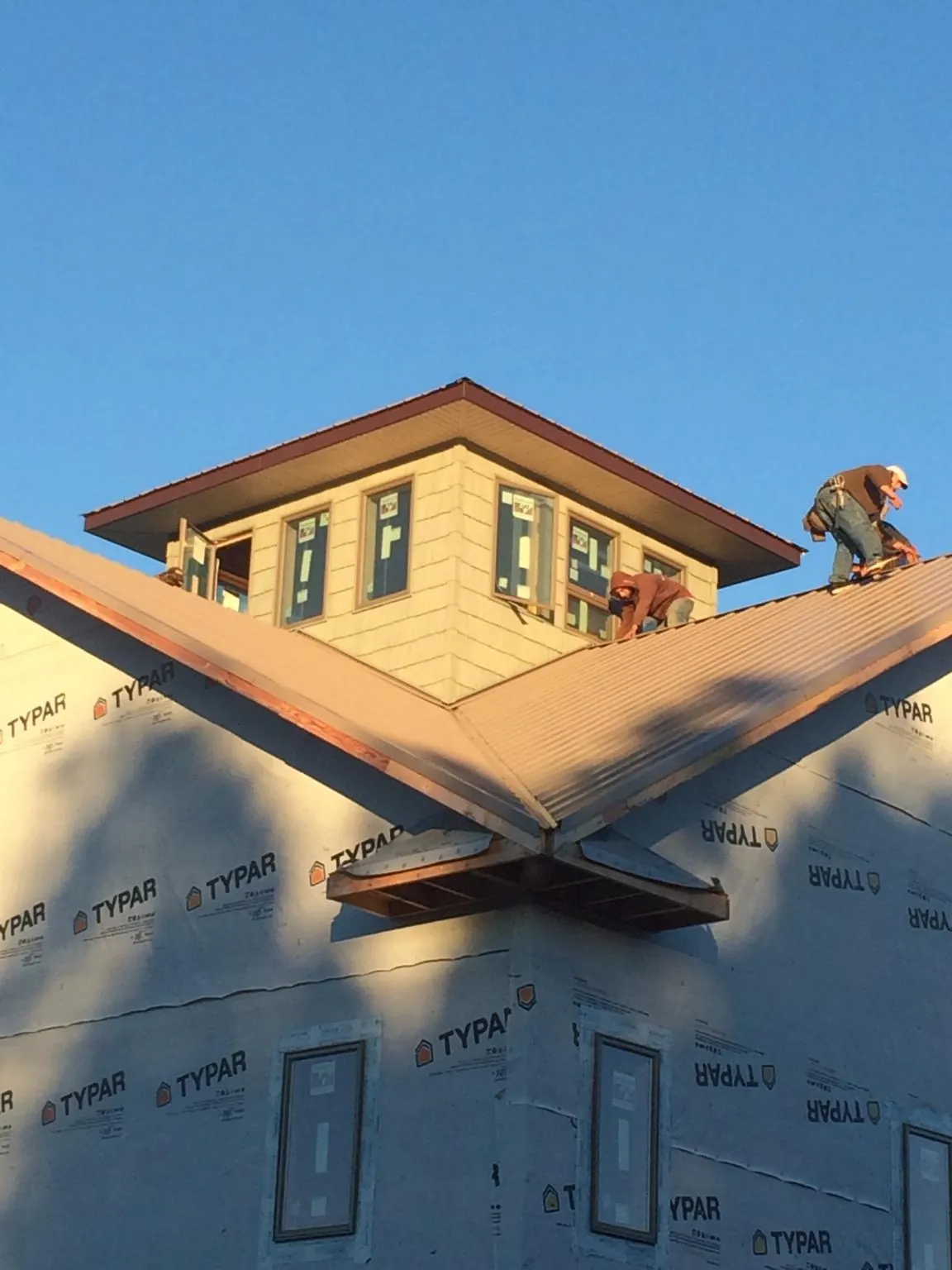 Roofers working around a rooftop cupola on a new metal roof at sunset — Roof Waterproofing in Wyandanch by Roofing Brothers
